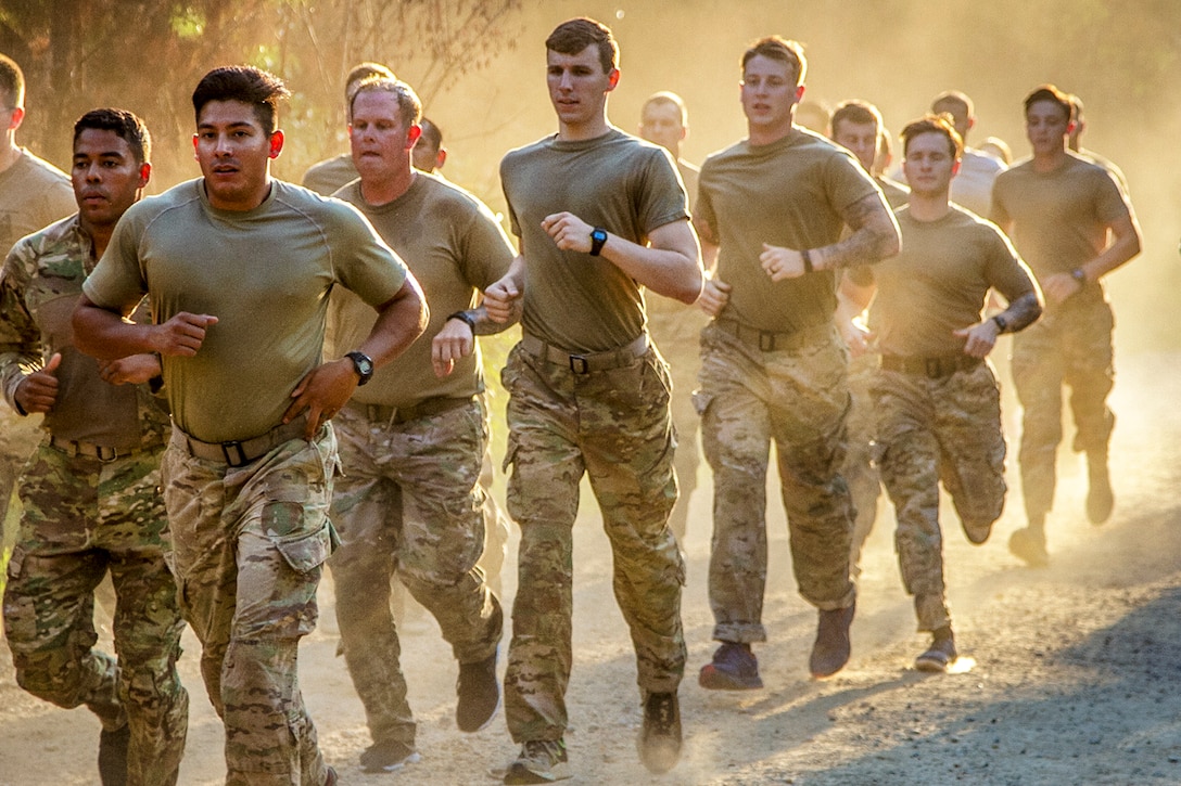 Soldiers run in formation in sunlight.