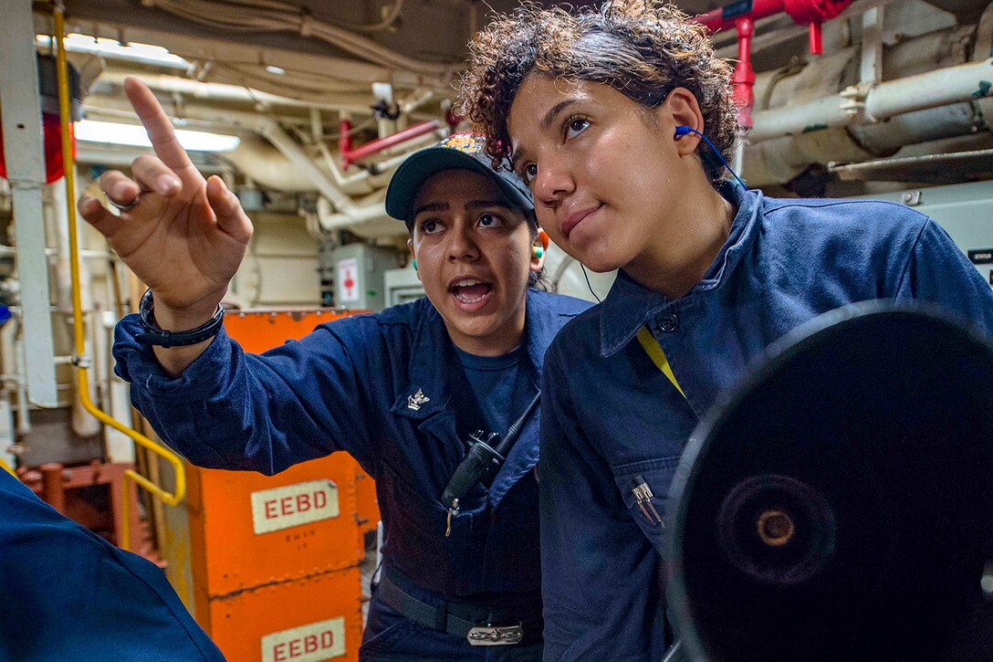 A sailor points and speaks to another sailor.