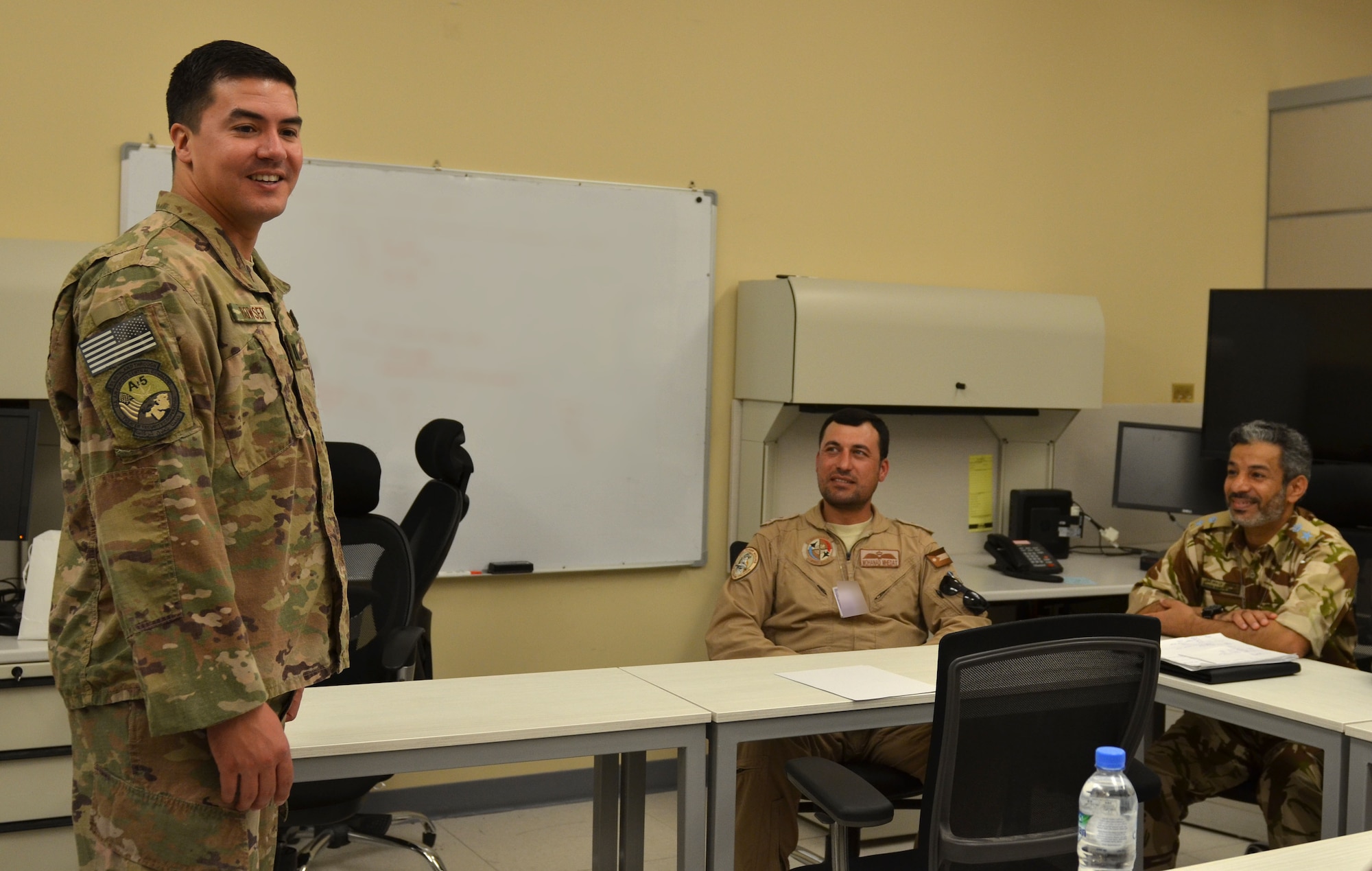 U.S. Air Force Capt. Christopher Bowser, Air Forces Central Command Coalition Coordination Cell deputy chief, talks with Coalition partners attending the Senior Planner Course, July 2, 2018 at Al Udeid Air Base, Qatar. Bowser is a fifth grade math and science teacher in western Pennsylvania.  (U.S. Air Force photo illustration by Staff Sgt. Stephanie Serrano) (This image was blurred for security reasons.)