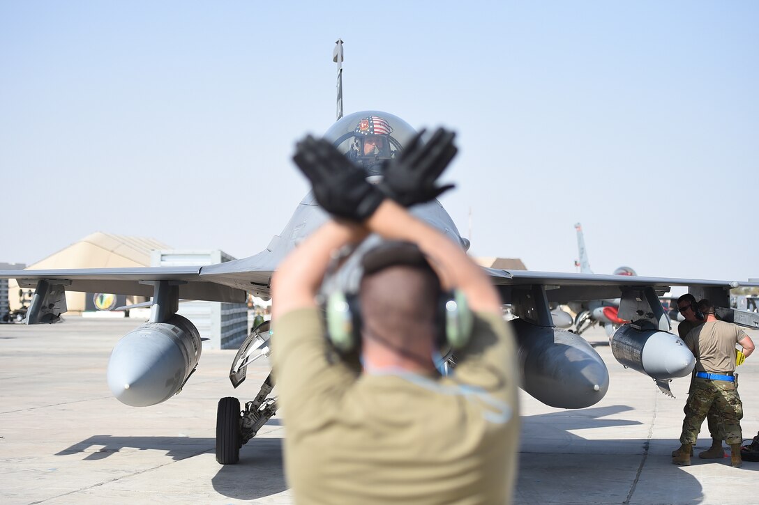 a airman uses hand signals to motion to a jet to stop moving