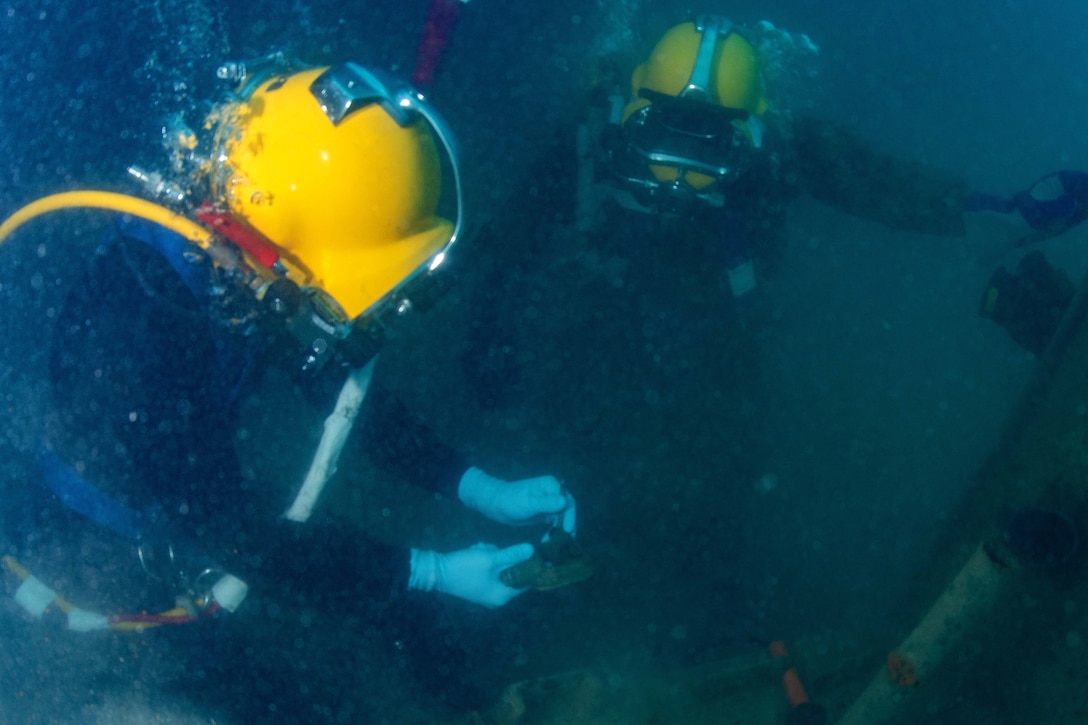 Sailors prepare a worksite during underwater welding operation.