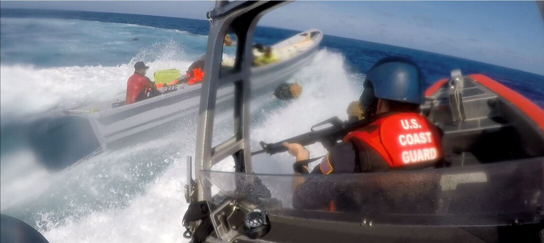 A U.S. Coast Guardsman aboard an interceptor boat pursues a suspected smuggling vessel