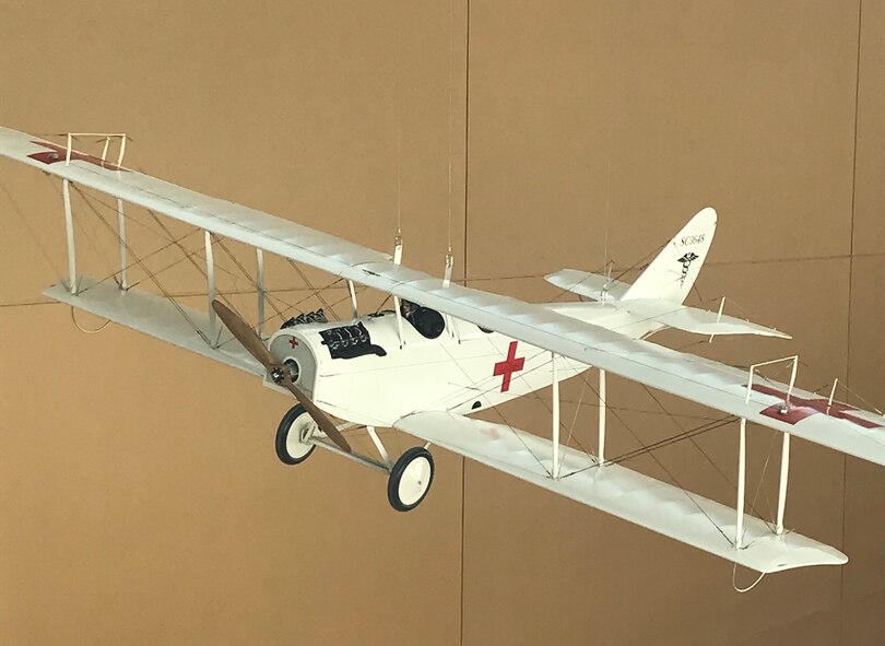 A model of a “Jenny”, a Curtiss JN-4, hangs above the atrium in USAFSAM. The “Jenny” was the first aircraft deemed as the first air ambulance. At the end of World War I, the United States Army recognized the need to air transport wounded soldiers. In 1918 Maj. Nelson E. Driver and Capt. William C. Ocker modified a Curtiss JN-4 “Jenny” bi-plane to accommodate a stretcher in order to transport patients. (U.S. Air Force Photo/Stacey Geiger)