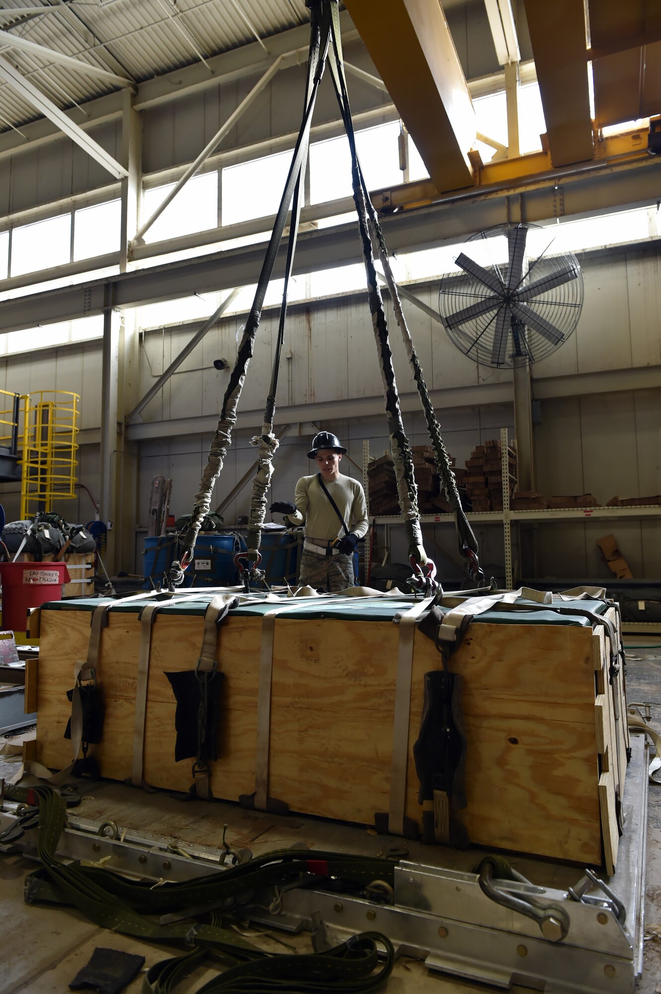 U.S. Air Force Senior Airman Travis Skelton, an air freight specialist assigned to the 97th Logistics Readiness Squadron, uses an overhead crane to lift aerial delivery cargo to be used for training purposes, Feb. 12, 2018, at Altus Air Force Base, Okla.