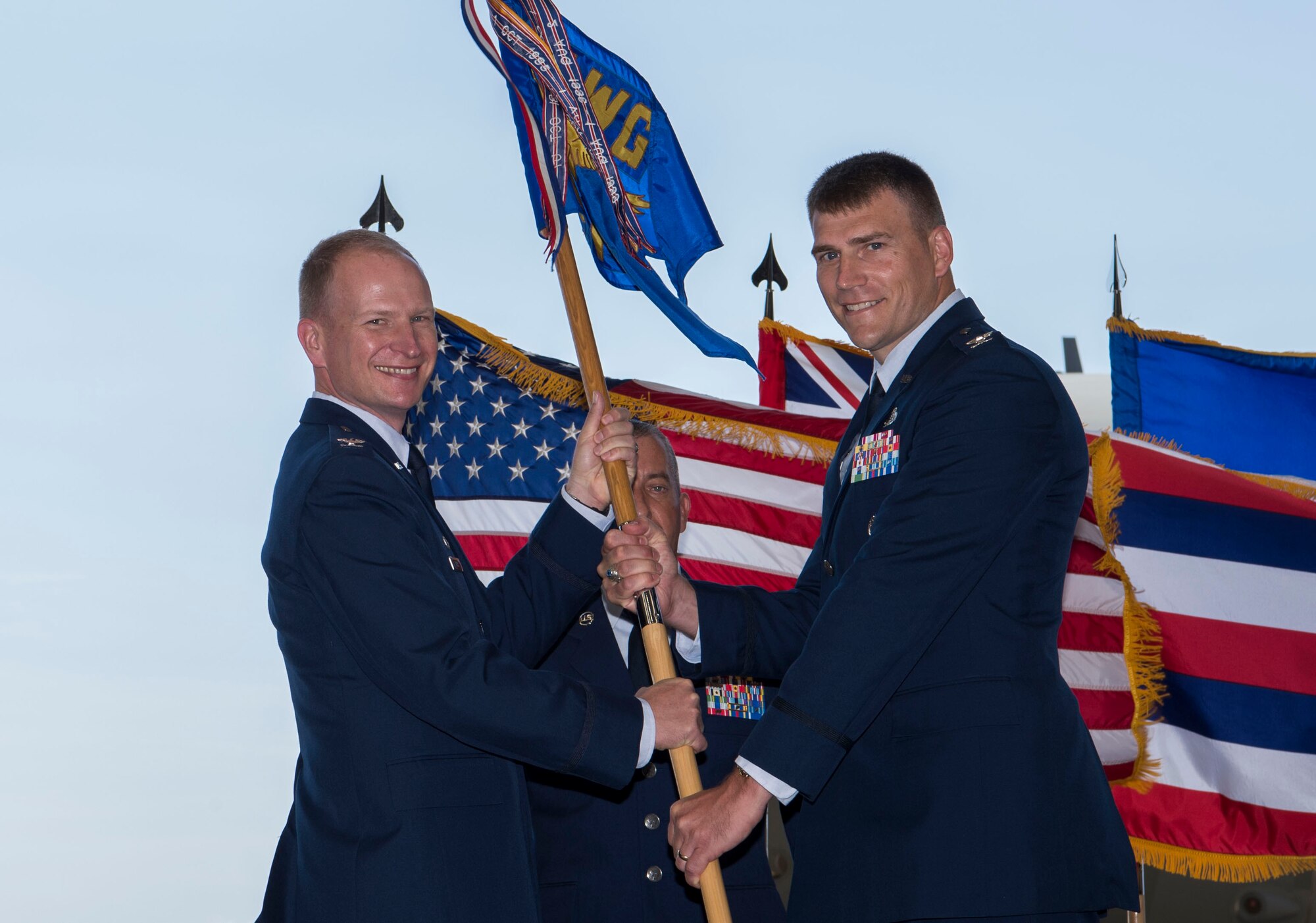 Col. Halsey Burks, 15th Wing commander, hands the 15th Maintenance Group flag to Col. Dominic Clementz, 15th MXG commander, during a change of command ceremony, Joint Base Pearl Harbor-Hickam, Hawaii, July 16, 2018. The MXG supports 31 home station aircraft to meet global airlift, global strike and theater security mission requirements and provides support to over 7,200 joint and allied aircraft transiting through Hickam Field each year. (U.S. Air Force photo by Tech. Sgt. Heather Redman)