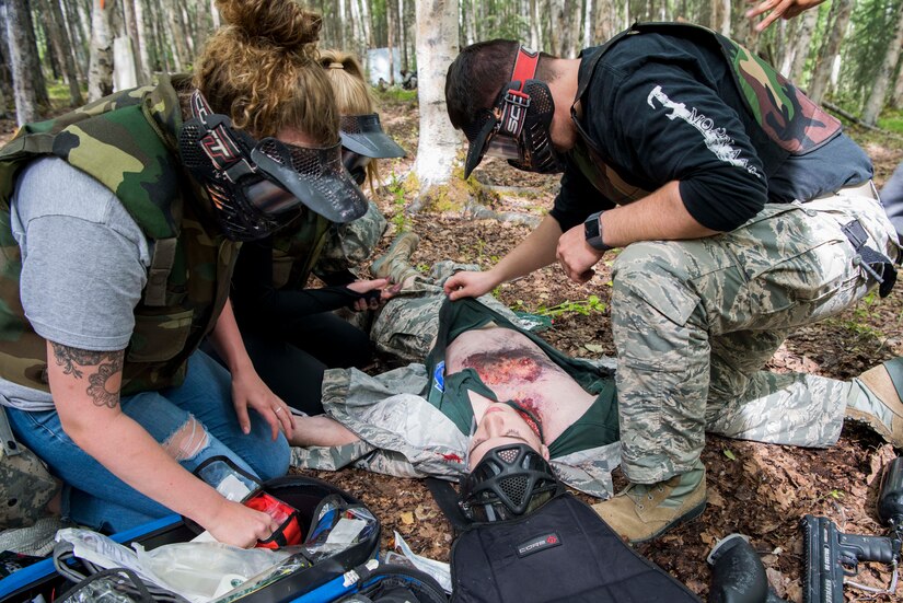 Personnel from the 673d Medical Group search for injuries during the practical application of the Tactical Combat Casualty Care course at the Warrior Extreme Paintball course at Joint Base Elmendorf-Richardson, Alaska, July 13, 2018. The course is an opportunity for every student to provide care under fire, perform tactical field care on those who are injured and execute a tactical evacuation.