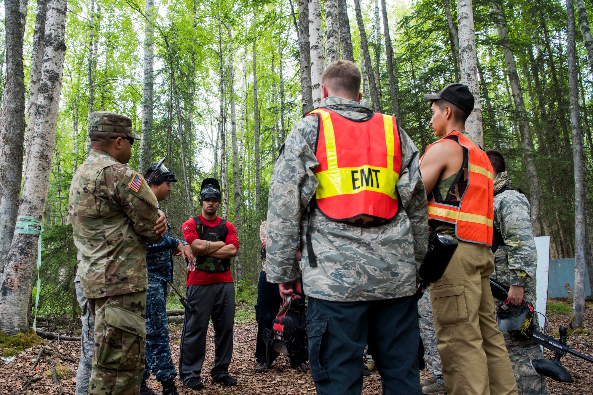 Tactical Combat Casualty Care instructors discuss strategic plans during the practical application of the TCCC course at the Warrior Extreme Paintball course at Joint Base Elmendorf-Richardson, Alaska, July 13, 2018. The course is an opportunity for every student to provide care under fire, perform tactical field care on those who are injured and execute a tactical evacuation.