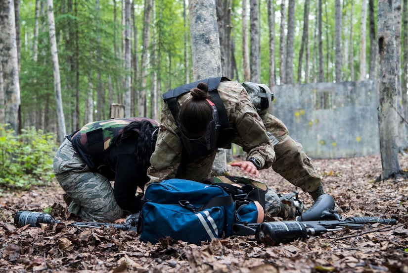 Personnel from the 673d Medical Group take cover and protect the “patient” while under fire during the practical application of the Tactical Combat Casualty Care course at the Warrior Extreme Paintball course at Joint Base Elmendorf-Richardson, Alaska, July 13, 2018. The course is an opportunity for every student to provide care under fire, perform tactical field care on those who are injured and execute a tactical evacuation.