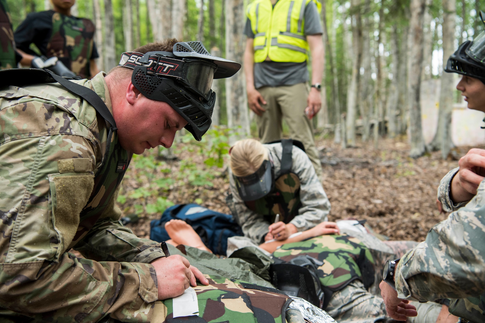 Personnel from the 673d Medical Group write an assessment during the practical application of the Tactical Combat Casualty Care course at the Warrior Extreme Paintball course at Joint Base Elmendorf-Richardson, Alaska, July 13, 2018. The course is an opportunity for every student to provide care under fire, perform tactical field care on those who are injured and execute a tactical evacuation.
