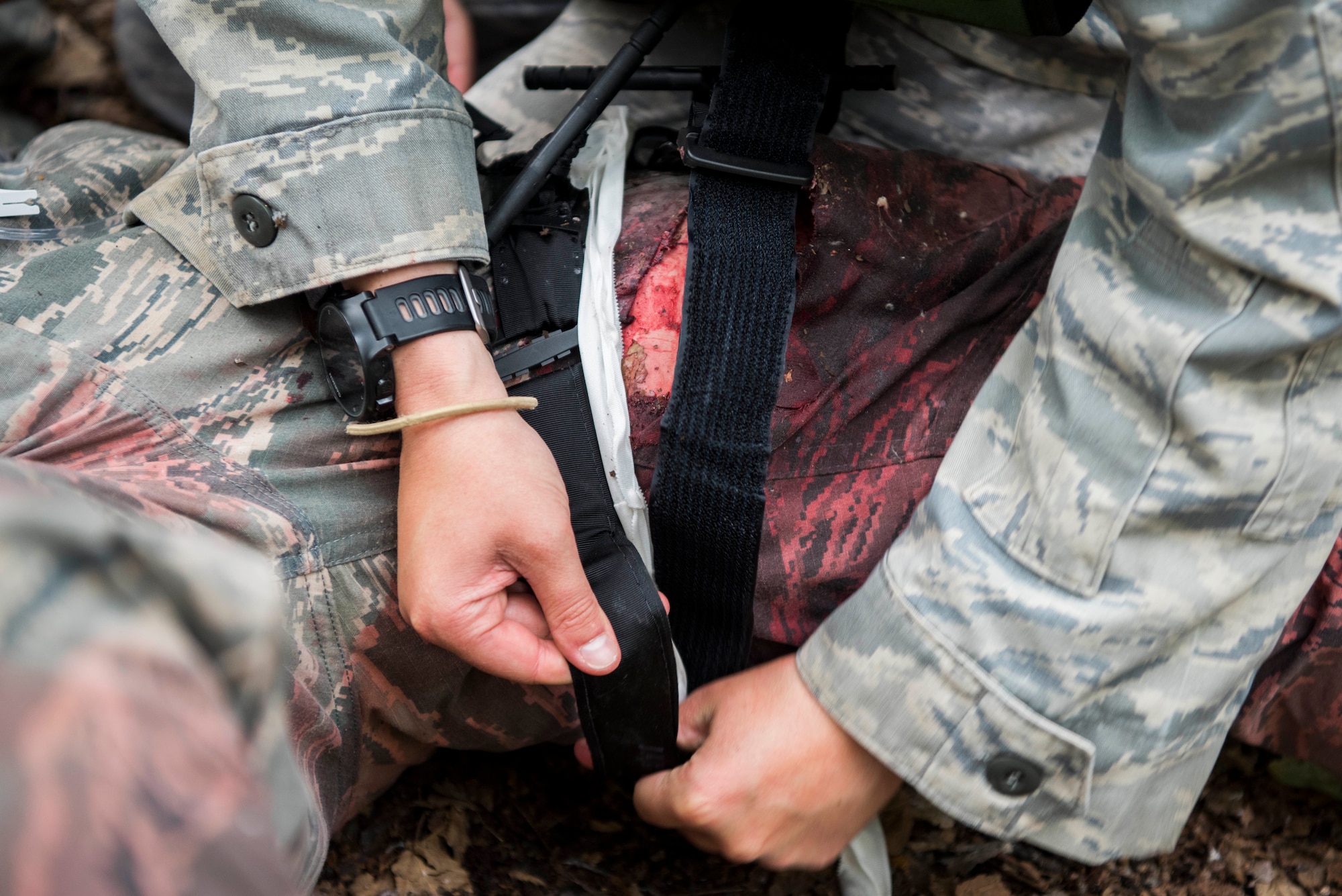 Personnel from the 673d Medical Group apply a tourniquet to an injured “patient” during the practical application of the Tactical Combat Casualty Care course at the Warrior Extreme Paintball course at Joint Base Elmendorf-Richardson, Alaska, July 13, 2018. The course is an opportunity for every student to provide care under fire, perform tactical field care on those who are injured and execute a tactical evacuation.