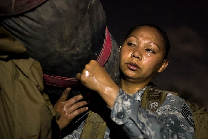 An airman carries a large heavy bag.