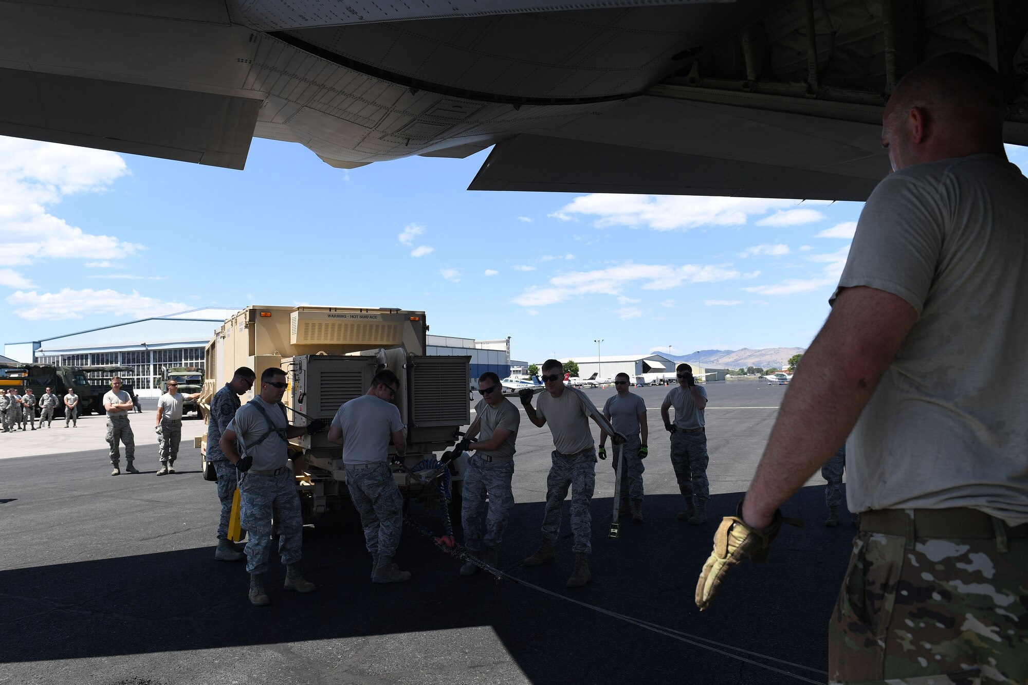 Airman directs other Airmen steering large object.