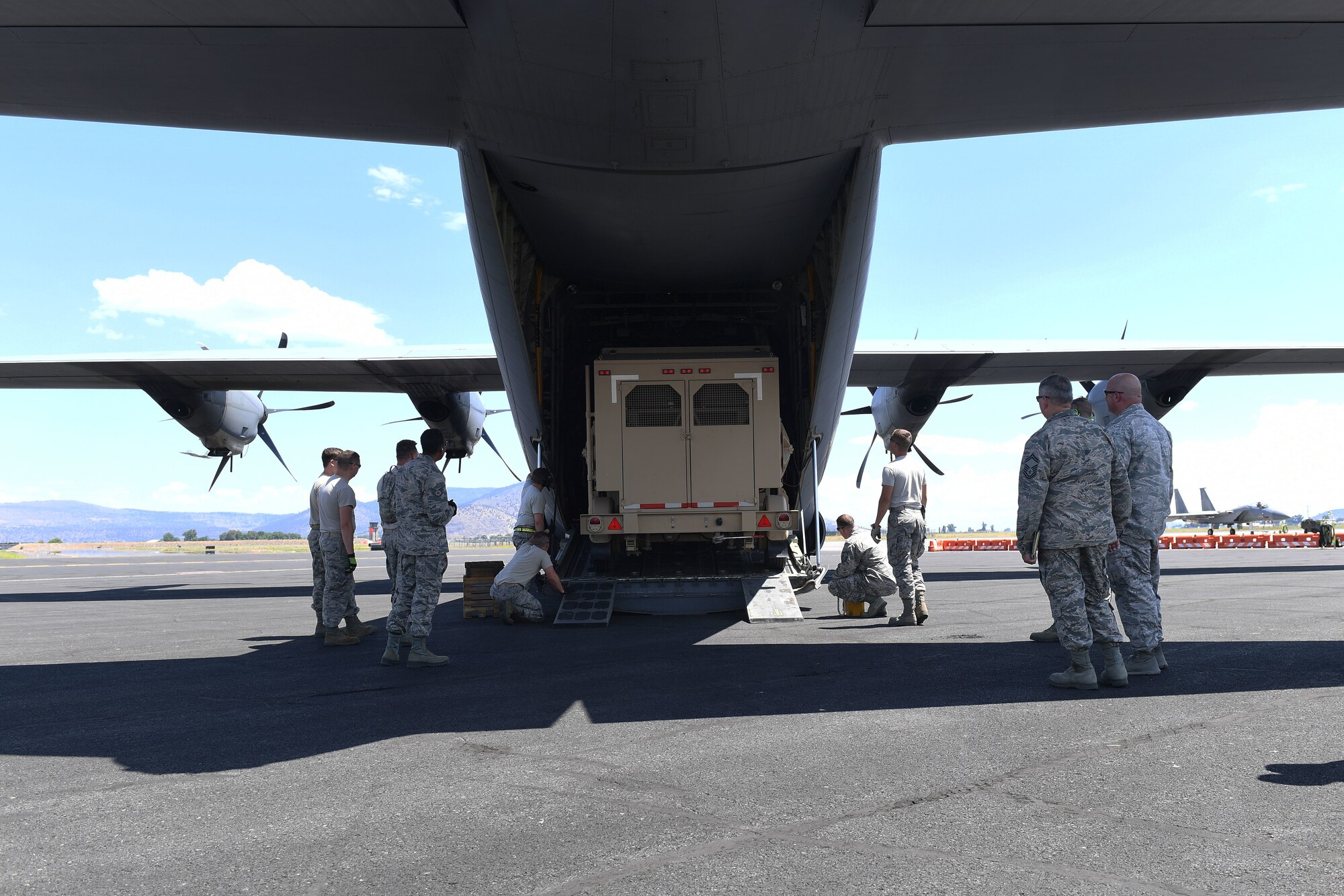 Airmen load a large piece of equipment onto plane.
