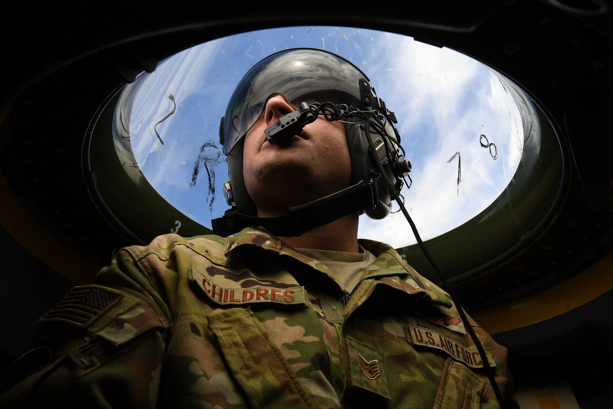 Airman looks over top of plane through plastic bubble.
