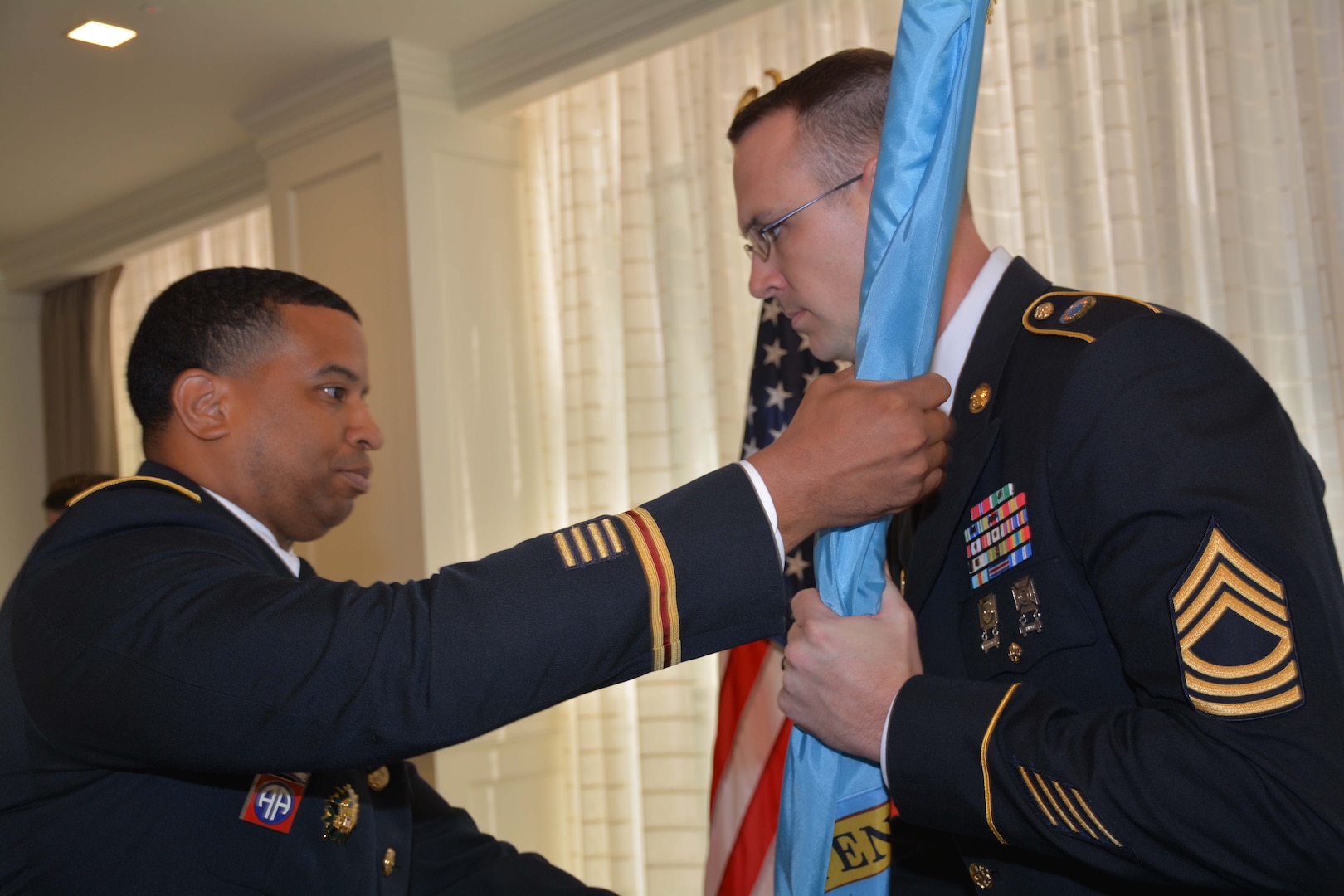 Army officer hands flag to Army NCO.