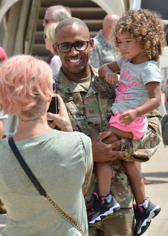 U.S. Air Force Tech. Sgt. Leon Pennyfeather, a combat crew communications technician with the 507th Operations Support Squadron at Tinker Air Force Base, Okla., holds his daughter while his wife snaps a photograph upon returning from deployment July 7, 2018. More than 100 Reserve Citizen Airmen from the 507th ARW at Tinker AFB deployed to Incirlik Air Base, Turkey, in support of air operations. (U.S. Air Force photo by Master Sgt. Grady Epperly)