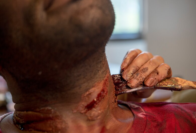Right, U.S. Army Spc. Sophia Matozzi, U.S. Army Medical Activity laboratory technician, applies moulage to a volunteer prior to an aircraft crash exercise at Joint Base Langley-Eustis, Virginia, July 17, 2018.