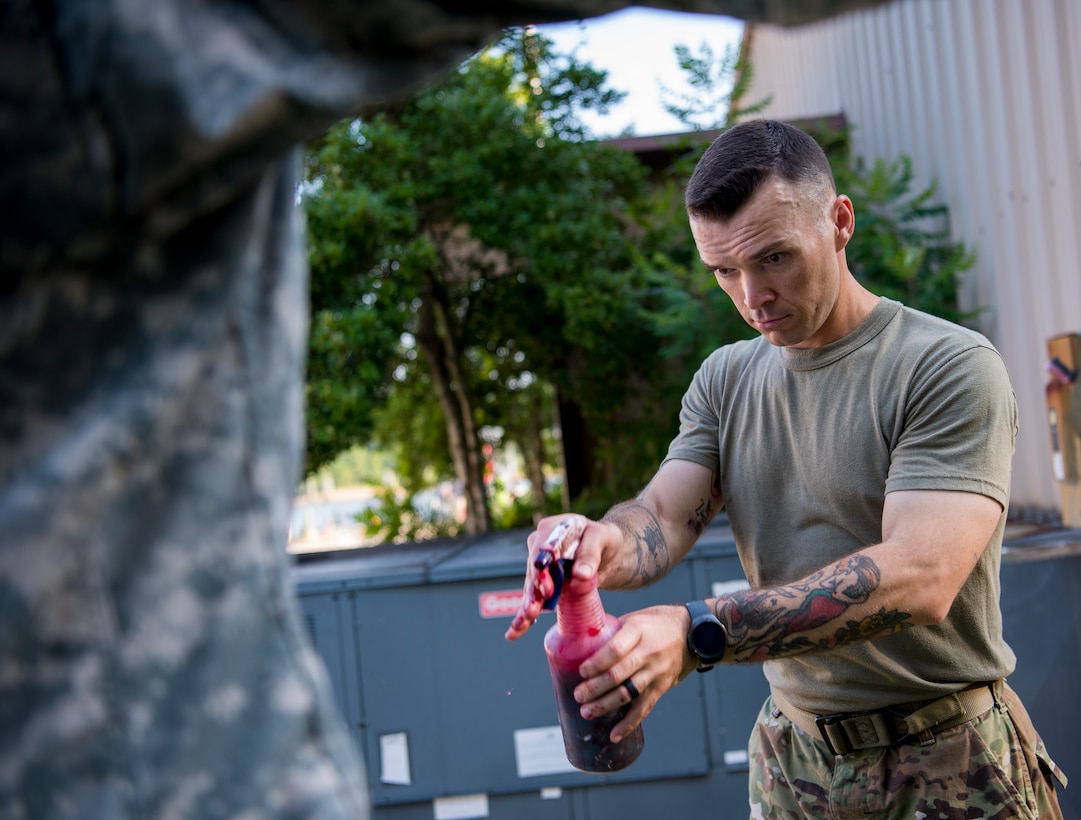 U.S. Army Staff Sgt. Chase Johnson, U.S. Army Medical Activity operations NCO, applies moulage to a volunteer prior to an aircraft crash exercise at Joint Base Langley-Eustis, Virginia, July 17, 2018.