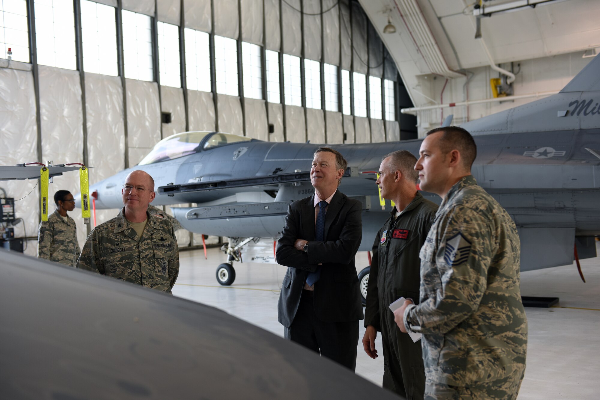 Gov. John Hickenlooper of Colorado, receives a brief on the Colorado Air National Guard’s F-16 Falcon’s mission capabilities from Col. Brian Turner, second from right, 140th Wing commander, at Buckley Air Force Base, Colorado, July 17, 2018.