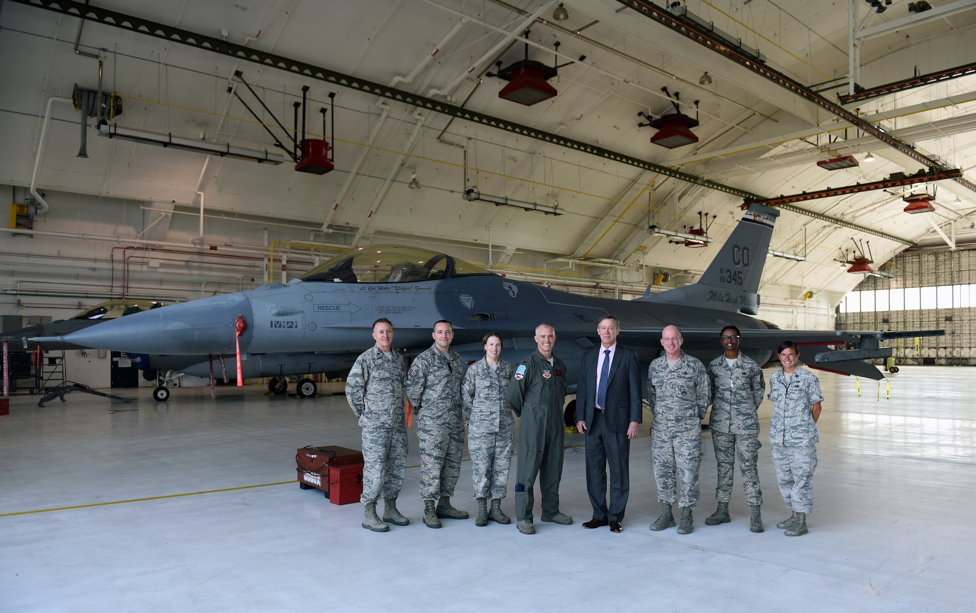 Members of Team Buckley stand with Gov. John Hickenlooper of Colorado in front of a F-16 Falcon assigned to the Colorado Air National Guard at Buckley Air Force Base, Colorado, July 17, 2018.