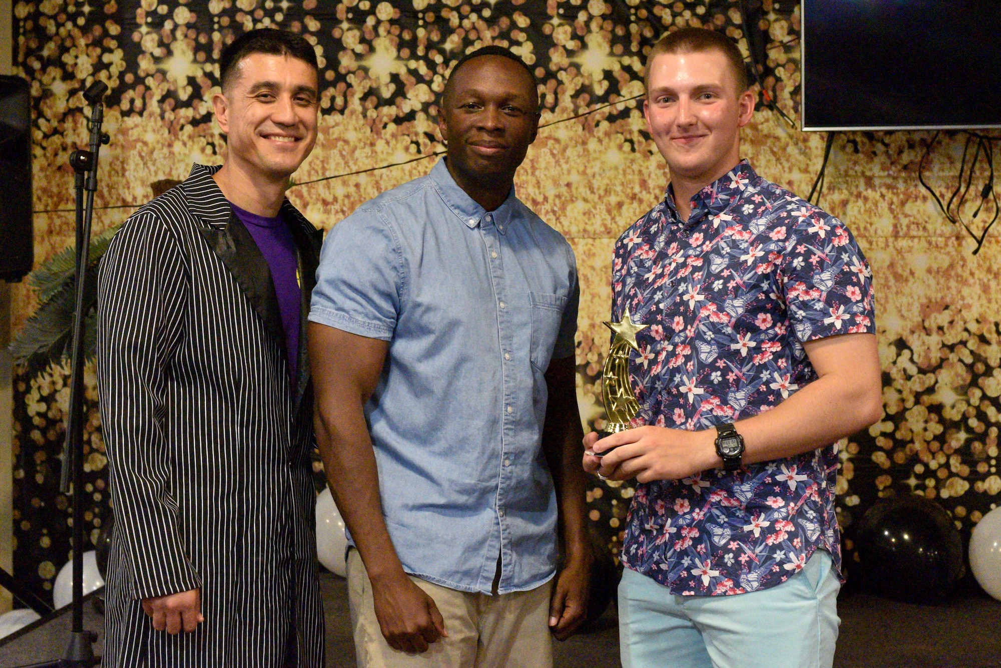 U.S. Air Force Col. Ricky Mills, 17th Training Wing commander and Chief Master Sgt. Lavor Kirkpatrick, 17th TRW command chief, present U.S. Army Pfc. Chris Frazier, 344th Military Intelligence Battalion student, an award for the semi-annual Goodfellow’s Got Talent show at the Crossroads Student Ministry Center on Goodfellow Air Force Base, Texas, July 13, 2018. Frazier won second place for his performance. (U.S. Air Force photo by Senior Airman Randall Moose/Released)