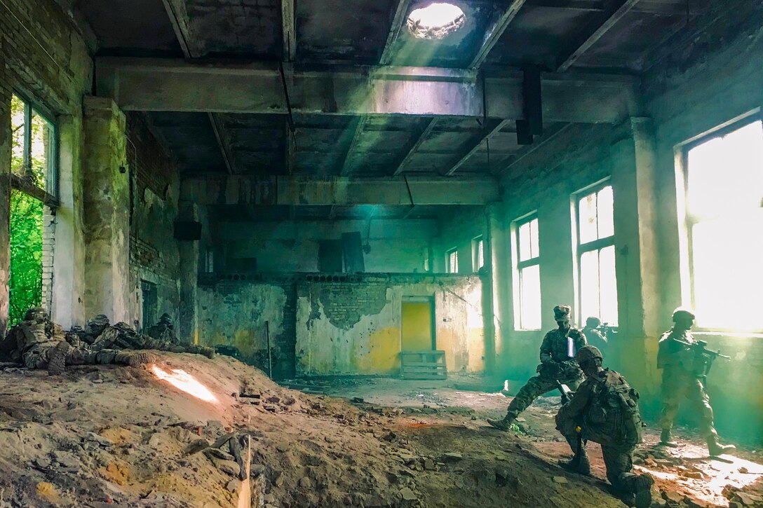 Soldiers stand in a room filled with dirt and green haze.
