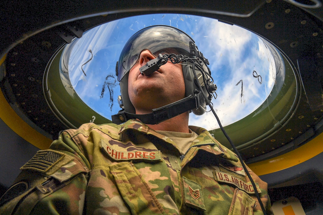 An airman looks at the sky through a window.