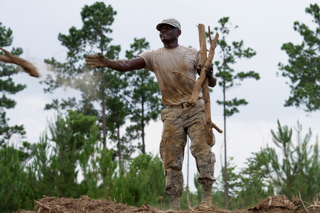 An airman tosses excess wood into a pile.