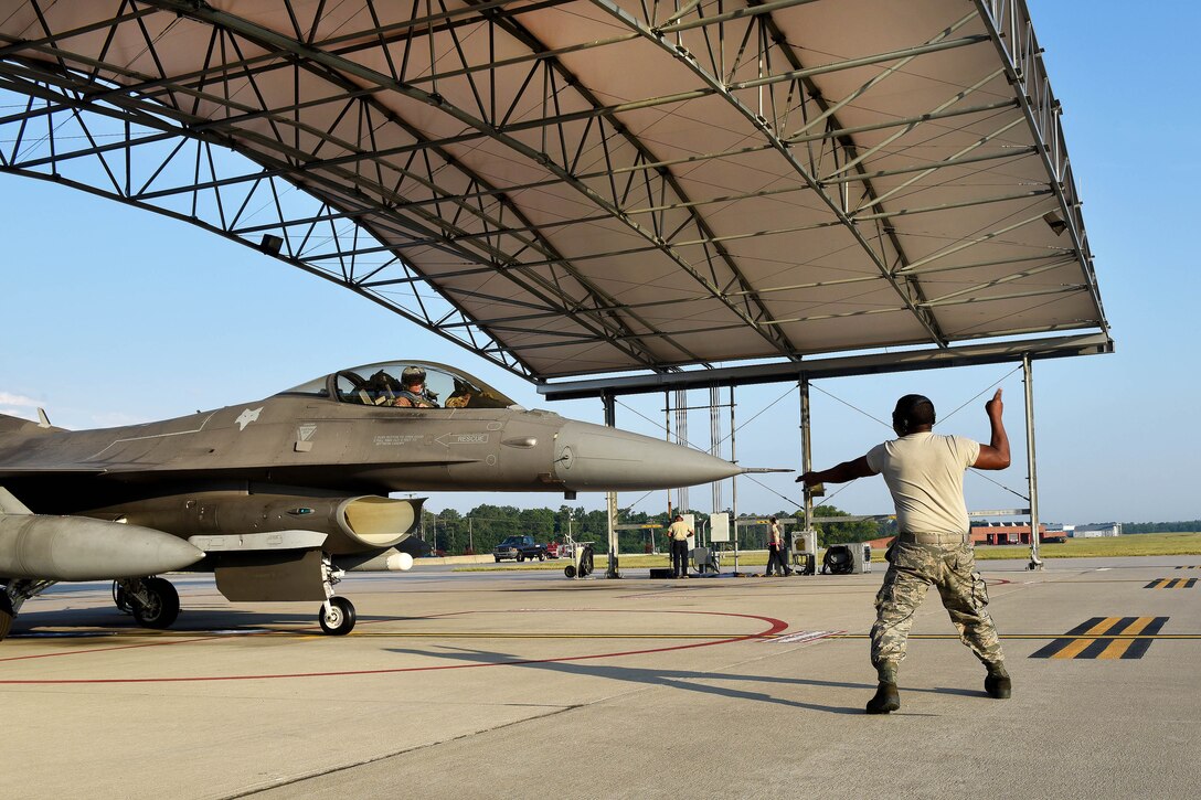 An airman directs a pilot to taxi an F-16 Fighting Falcon aircraft.
