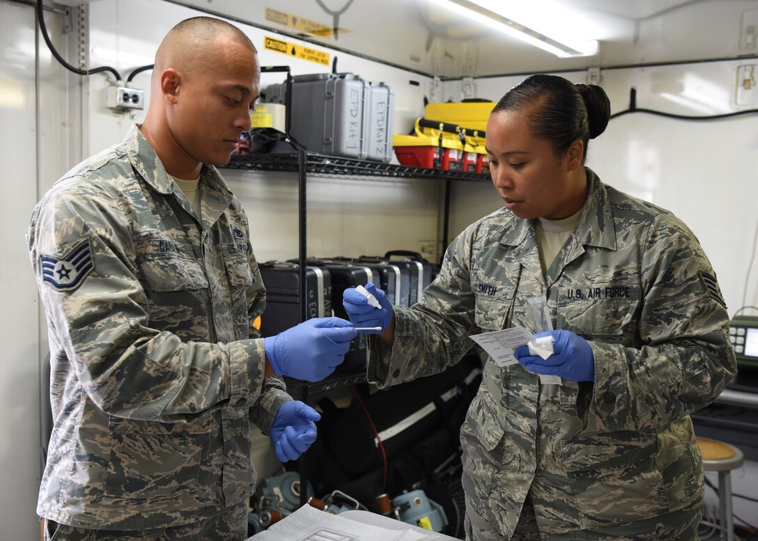 Staff Sgt. Michelle Smith, 51st Aerospace Medical Squadron NCO in charge of readiness plans and operations, demonstrates how to use a sampling kit to test for biological agents with Staff Sgt. Nikita Canalin, 51st Aircraft Maintenance Squadron avionics system technician, at Osan Air Base, Republic of Korea, July 9, 2018. During the Airman exchange, Canalin not only learned about day-to-day operations performed by medical technicians but also learned how to perform mission critical duties in a contingency. (U.S. Air Force photo by Airman 1st Class Ilyana A. Escalona)