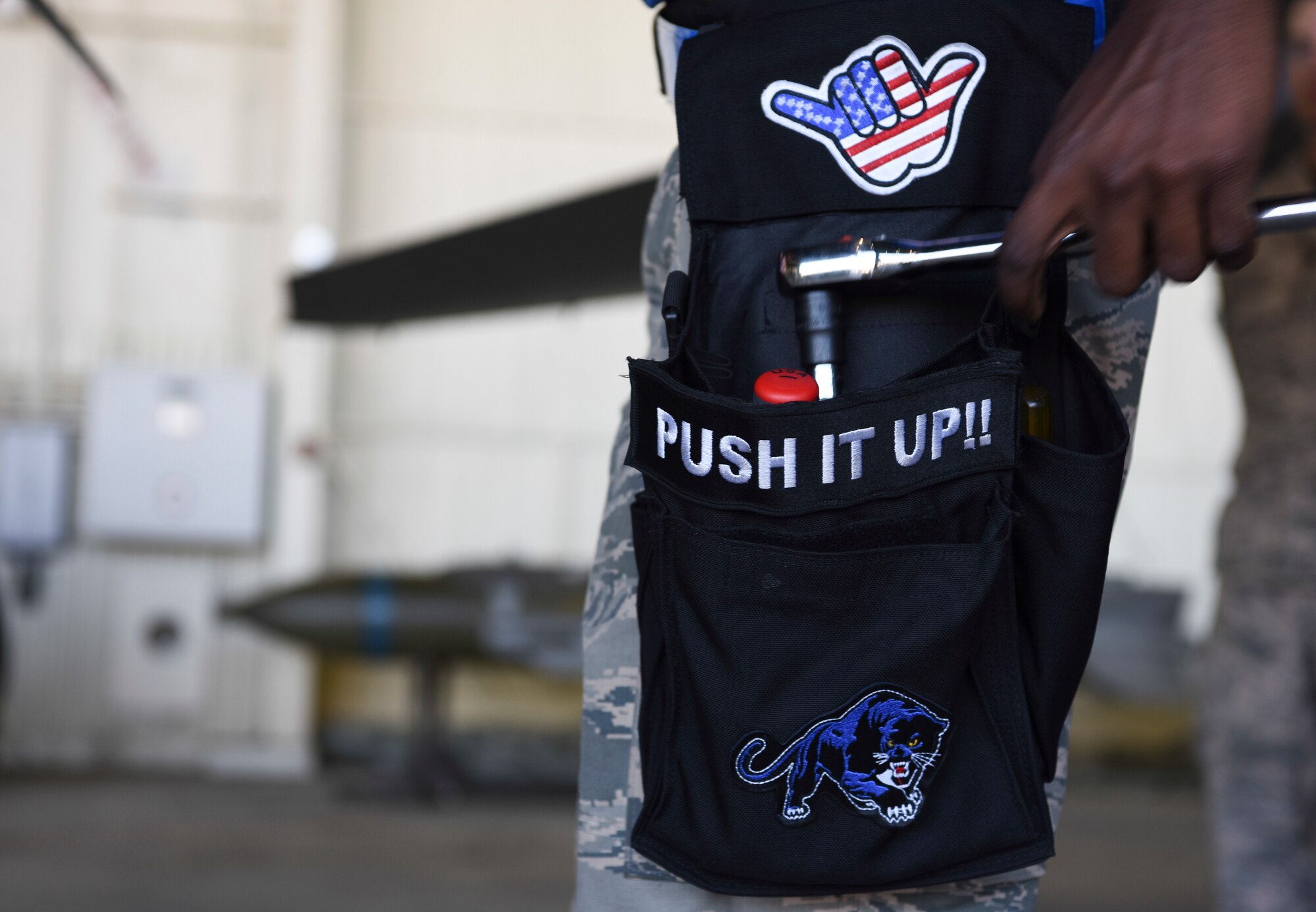 U.S. Air Force Staff Sgt. Jarron Roney, 35th Aircraft Maintenance Unit weapons load crew member, reaches into his tool pouch during the 8th Maintenance Group's 2nd Quarter Weapons Loading Competition at Kunsan Air Base, Republic of Korea, July 13, 2018. Airmen from the 35th AMU chanted, "Push it Up!” as competitors completed each challenge during the competition.