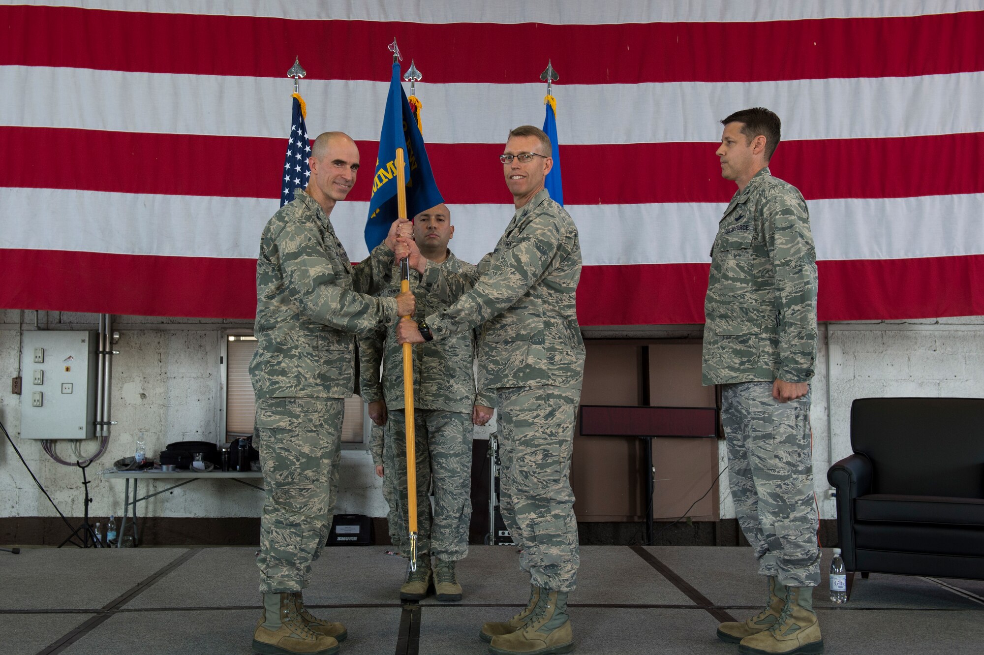 U.S. Air Force Col. Jason E. Bailey, 52nd Fighter Wing commander, left, passes the ceremonial guidon to Col. Greg Buckner, incoming 52nd Munitions Maintenance Group commander, right, during the 52 MMG change of command ceremony in Hangar 1 on Spangdahlem Air Base, Germany, July 17, 2018. (U.S. Air Force photo by Senior Airman Dawn M. Weber)