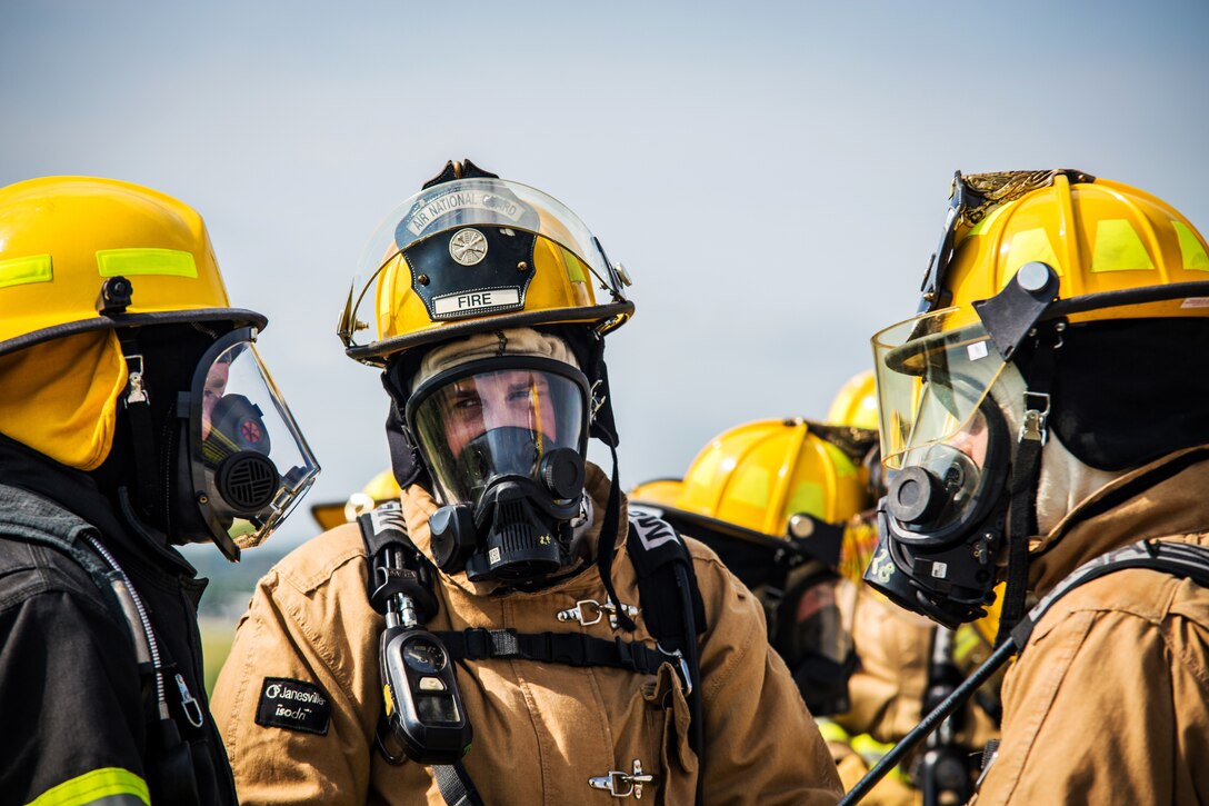 Firefighters put on protective gear prior to battling a simulated aircraft fire.