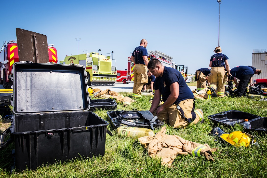 Firefighters pack up gear after fighting a simulated aircraft fire.