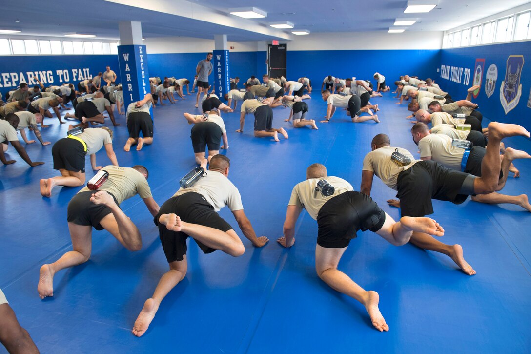 Airmen raise a leg from a mat to experience body mobility training.