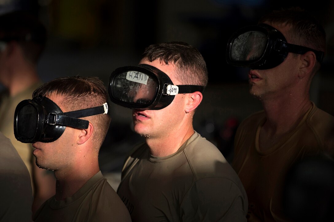 Airmen wearing swimming goggles wait in line for the next swimming lessons.
