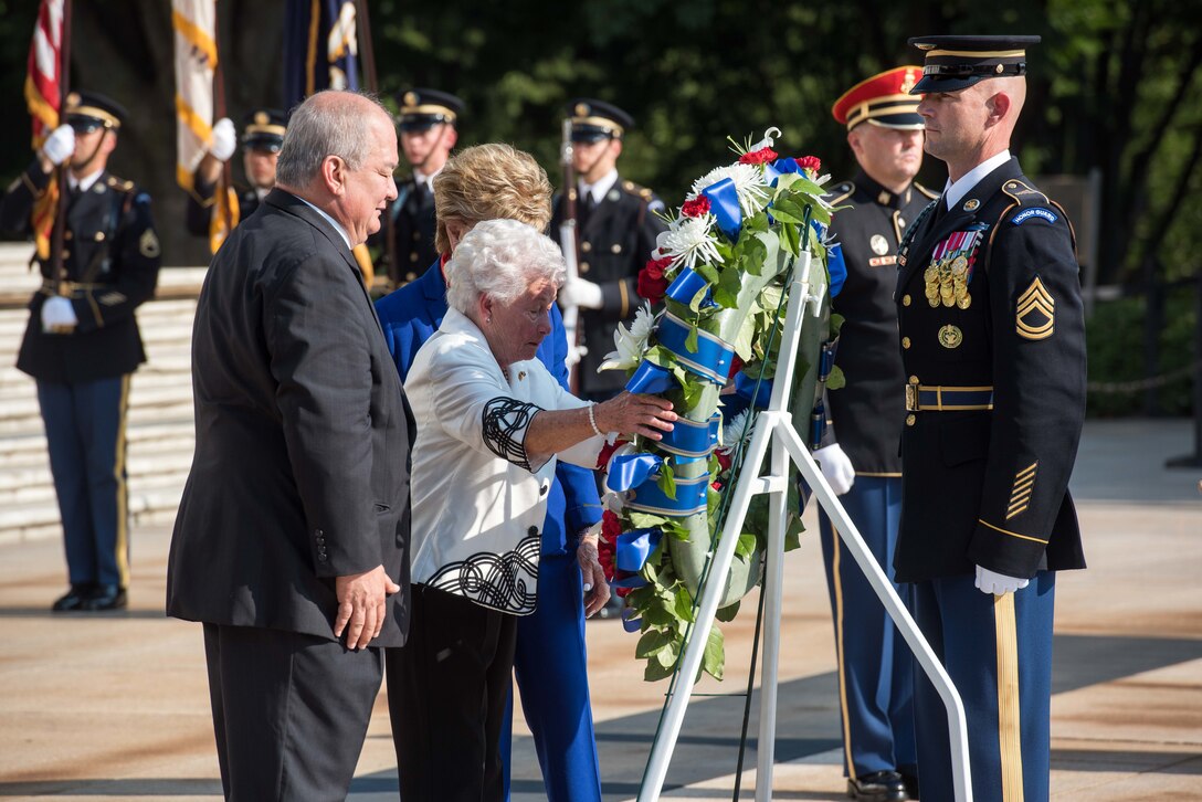 Woman helps soldier lay a wreath at the Tomb of the Unknown Soldier.