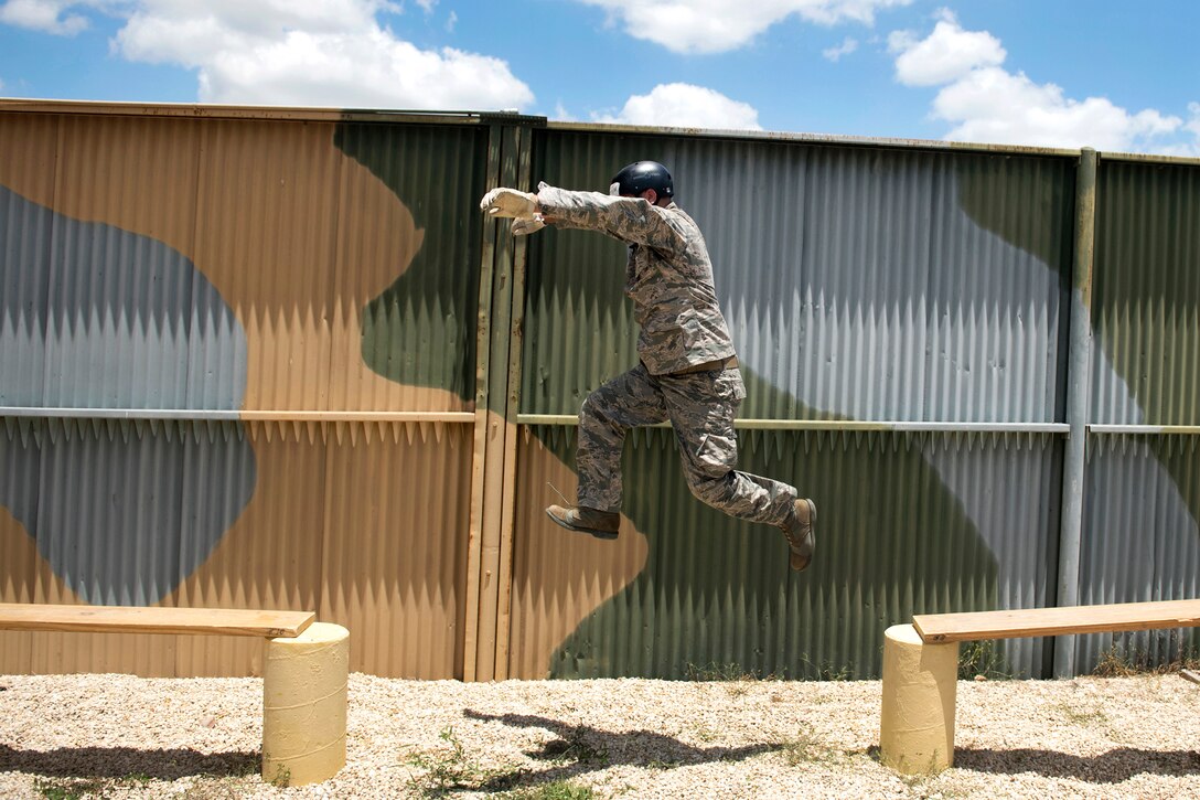 An airman leaps over a gap between planks during a leadership obstacle course.