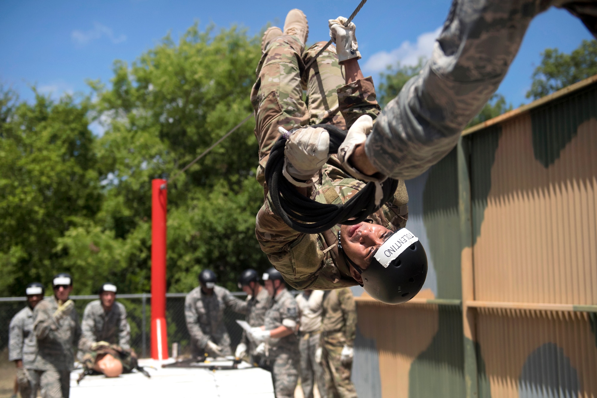 An airman navigates along a rope while upside-down during an obstacle course.