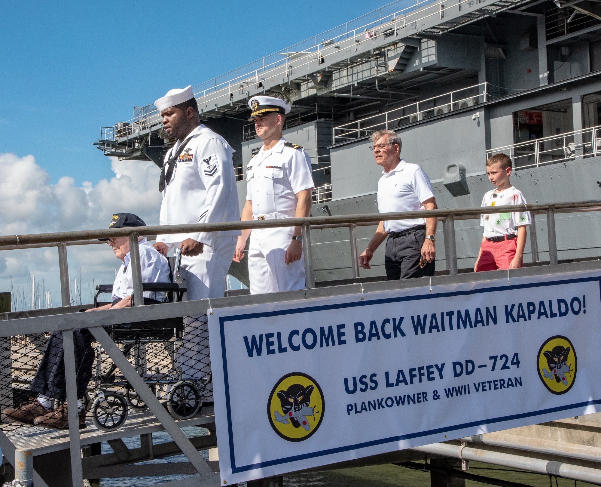 Petty Officer 2nd Class Clinton Leonard, second to left, a hospital corpsman serving at Naval Health Clinic Charleston, ushers WWII Veteran Waitman Kapaldo, left, across the brow to the USS Laffey July 6, 2018, at Patriots Point in Mount Pleasant, S.C., as Kapaldo visited the destroyer for the first time in 73 years. Kapaldo is a member of the Laffey’s original 1944 crew.