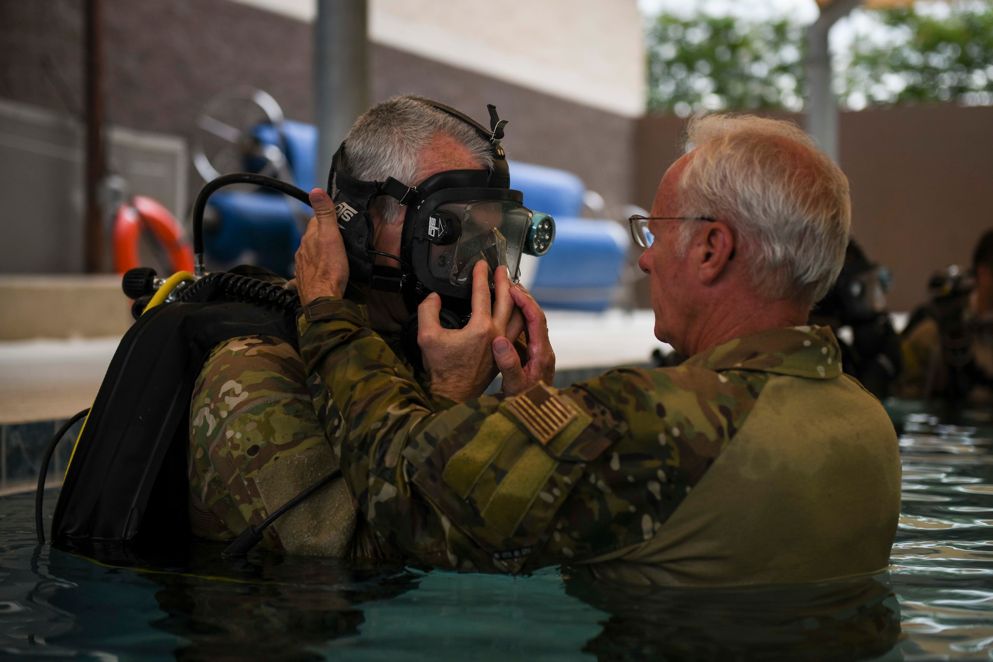 Two people performing equipment checks in a pool
