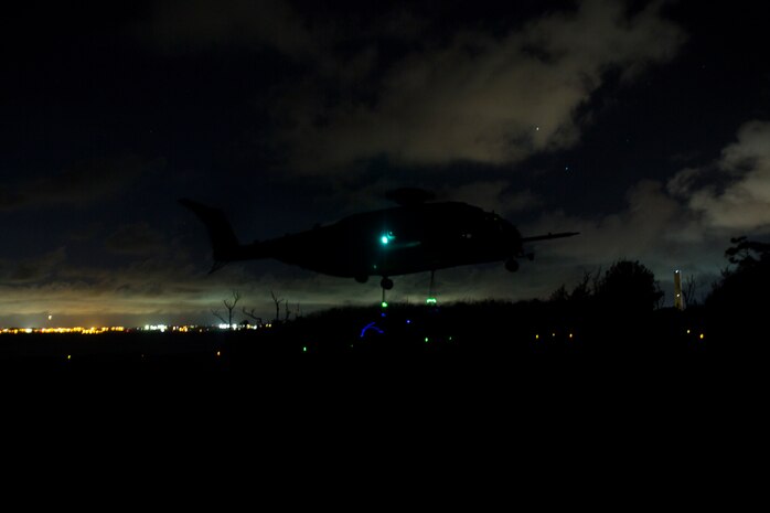 Landing support specialists with Landing Support Platoon, LS Company, 3rd Transportation Support Battalion, attach a training block to a CH-53E Super Stallion as it hovers over them July 13, 2018 at Kin Blue Training Area, Okinawa, Japan. LS Co. conducts training regularly to keep Marines proficient in their ability to aid III Marine Expeditionary Force in humanitarian operations and combat environments. (U.S. Marine Corps photo by Lance Cpl. Jamin M. Powell)