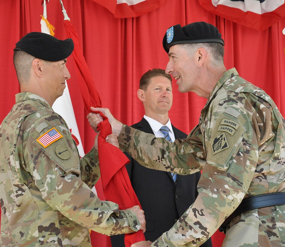 Brig. Gen. Pete Helmlinger, U.S. Army Corps of Engineers South Pacific Division commander, right, passes the flag to Col. Aaron Barta, incoming U.S. Army Corps of Engineers Los Angeles District commander, left, during a July 19 change of command ceremony at Fort MacArthur in San Pedro, California. The passing of the flag in military tradition represents the transfer of command.