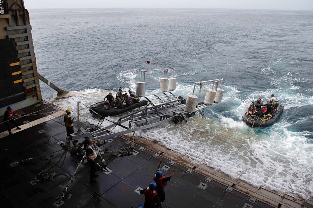 U.S. sailors prepare to recover Australian sailors in a combat rubber raiding craft.
