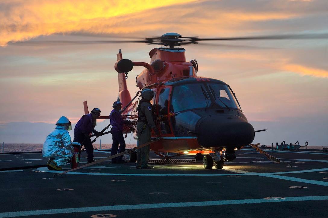 Coast Guard cutter crew refuels a helicopter.