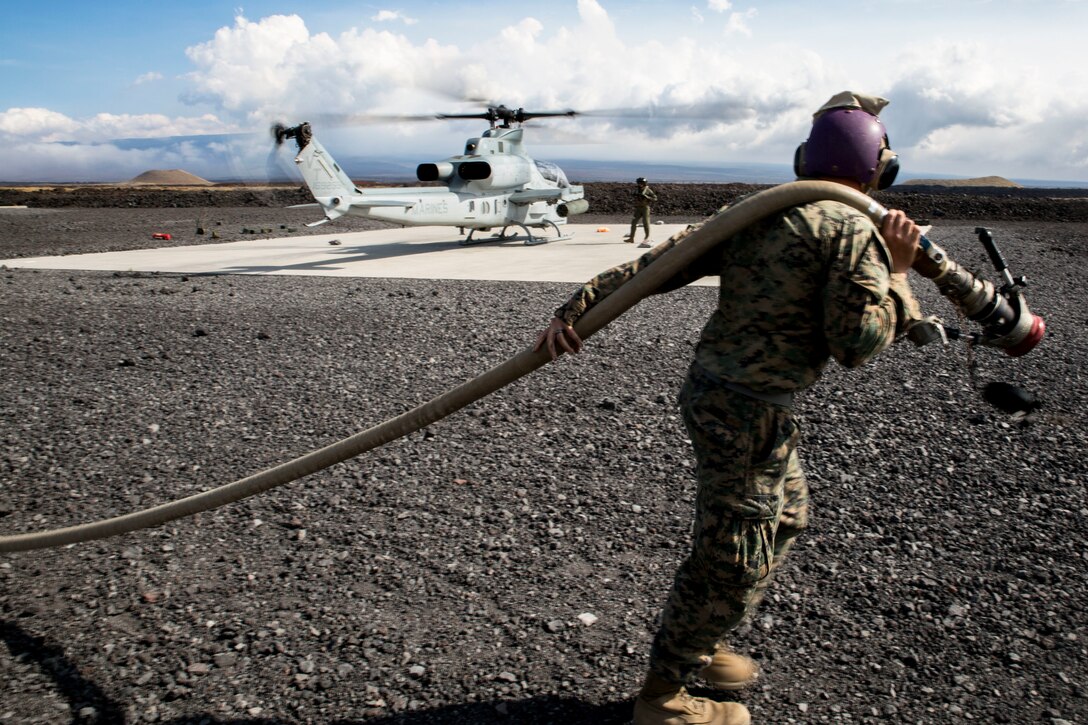 U.S. Marine Corps Cpl. Garrett Subik, a bulk fuel specialist with Marine Wing Support Detachment 24, moves a fuel line towards a landing pad in order to start fueling a AH-1W Super Cobra helicopter during a field test for an Expeditionary Mobile Fuel Additization Capability system as part of Rim of the Pacific (RIMPAC) exercise at Pohakuloa Training Area, Hawaii, July 18, 2018. RIMPAC provides high-value training for task-organized, highly capable Marine Air-Ground Task Force and enhances the critical crisis response capability of U.S. Marines in the Pacific.