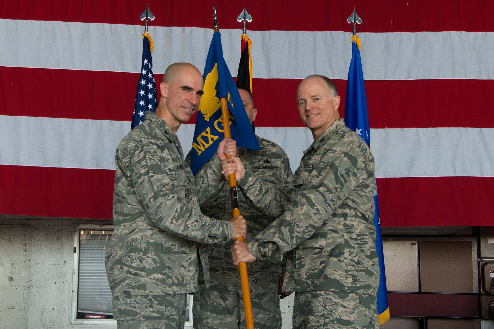 U.S. Air Force Col. Jason E. Bailey, 52nd Fighter Wing commander, left, passes the ceremonial guidon to Col. Timothy Trimmell, incoming 52nd Maintenance Group commander, during the 52nd MXG change of command ceremony in Hangar 1 at Spangdahlem Air Base, Germany, July 20, 2018. (U.S. Air Force photo by Airman 1st Class Jovante Johnson)