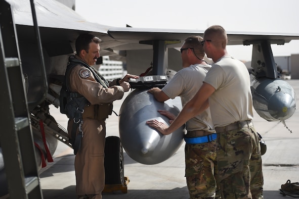 Airman talk with a pilot in front of an F-16 fighter jet