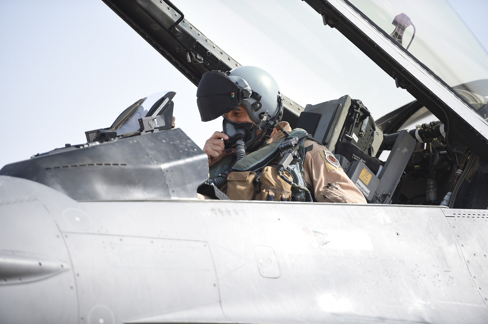A pilot sits in the cockpit of an F-16 fighter jet