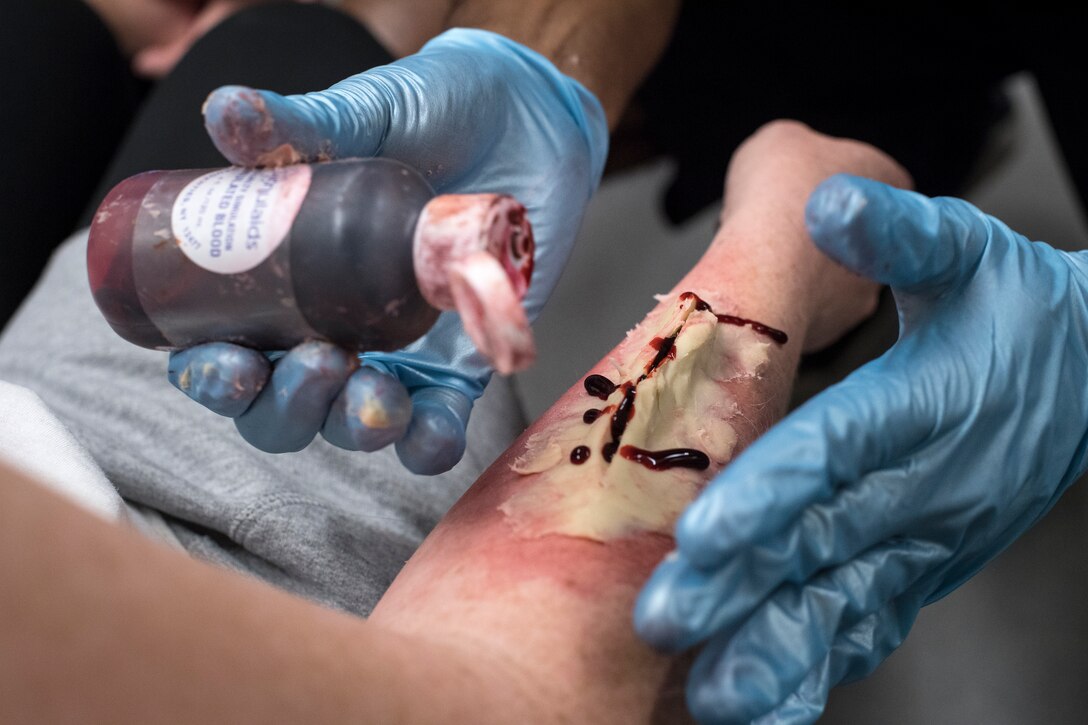 Airmen from the 23d Medical Group (MDG) create a fake wound on a simulated casualty during a mass casualty exercise, July 19, 2018, at Moody Air Force Base, Ga. The exercise tested the MDG’s emergency response capabilities during a chemical attack. (U.S. Air Force photo by Senior Airman Janiqua P. Robinson)